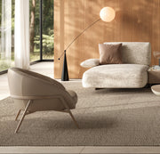 Modern living room with beige sofa, armchair, and coffee table in a well-lit room with wooden walls.