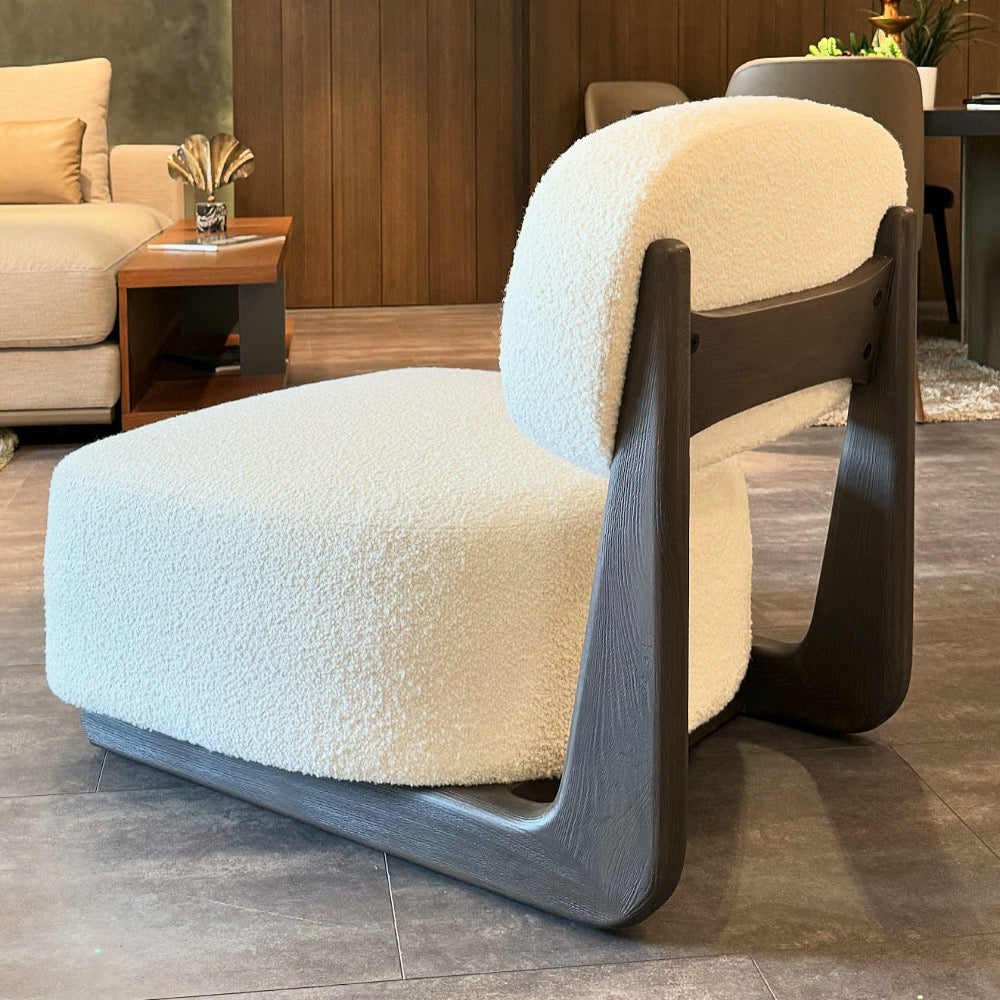 Aura armchair in a cozy living room with bouclé fabric and wooden back detail, styled with a large artwork