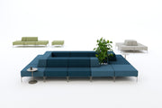Modern blue sofa with green plant and small round table on a white background